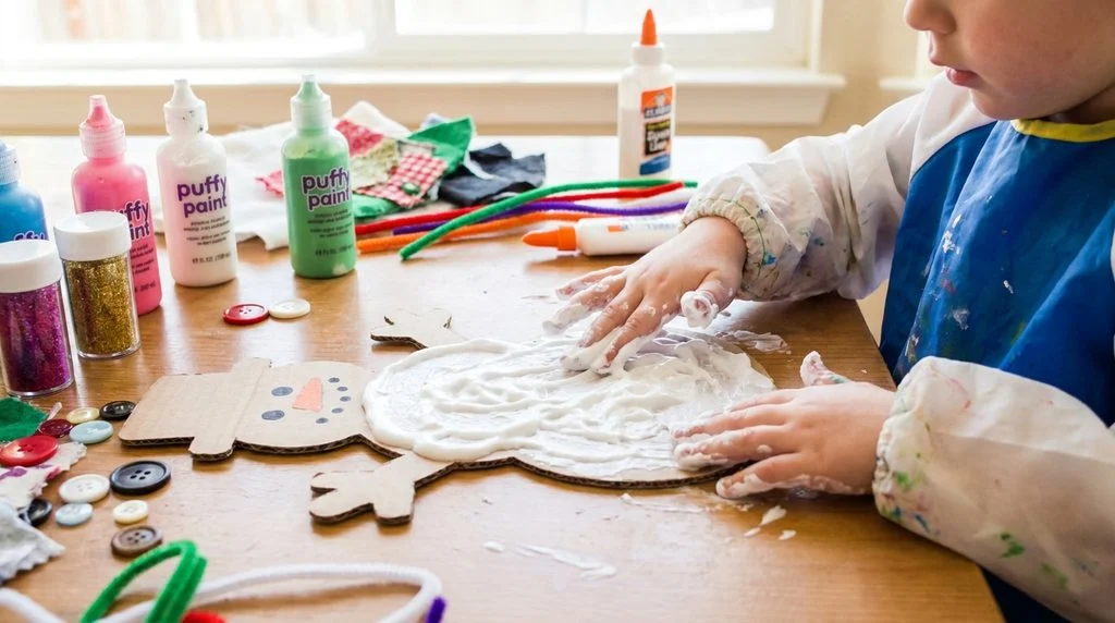 Child making a puffy paint snowman craft