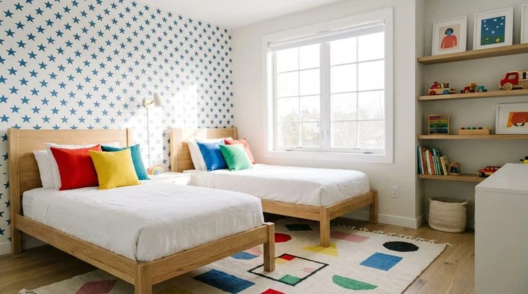 Timeless neutral shared kids' bedroom with wood beds, white walls, removable patterned accent wall, and swappable colorful accents.