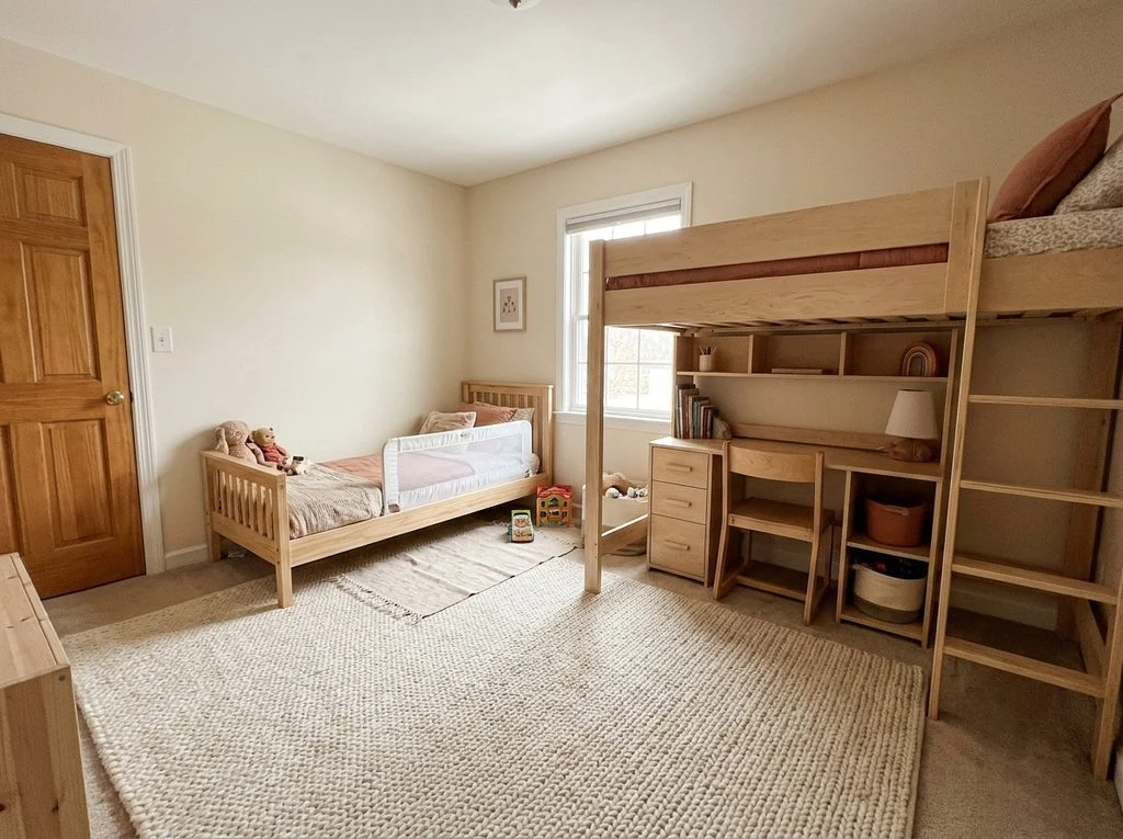 Shared room with a low toddler bed near the door and a loft bed with desk underneath for an older sibling