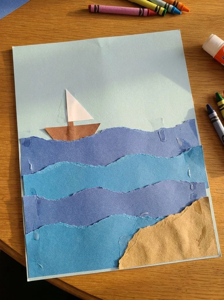 Layered blue paper waves with a small sailboat and a torn-paper beach.