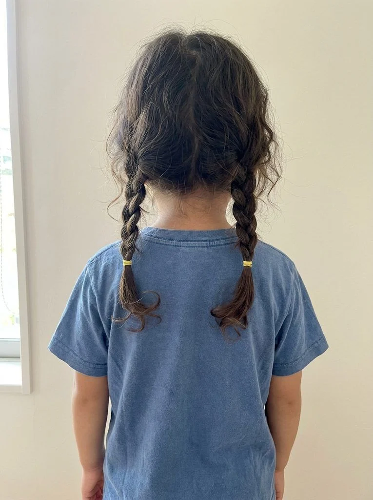 Two basic three-strand braids with yellow ties below a center part.