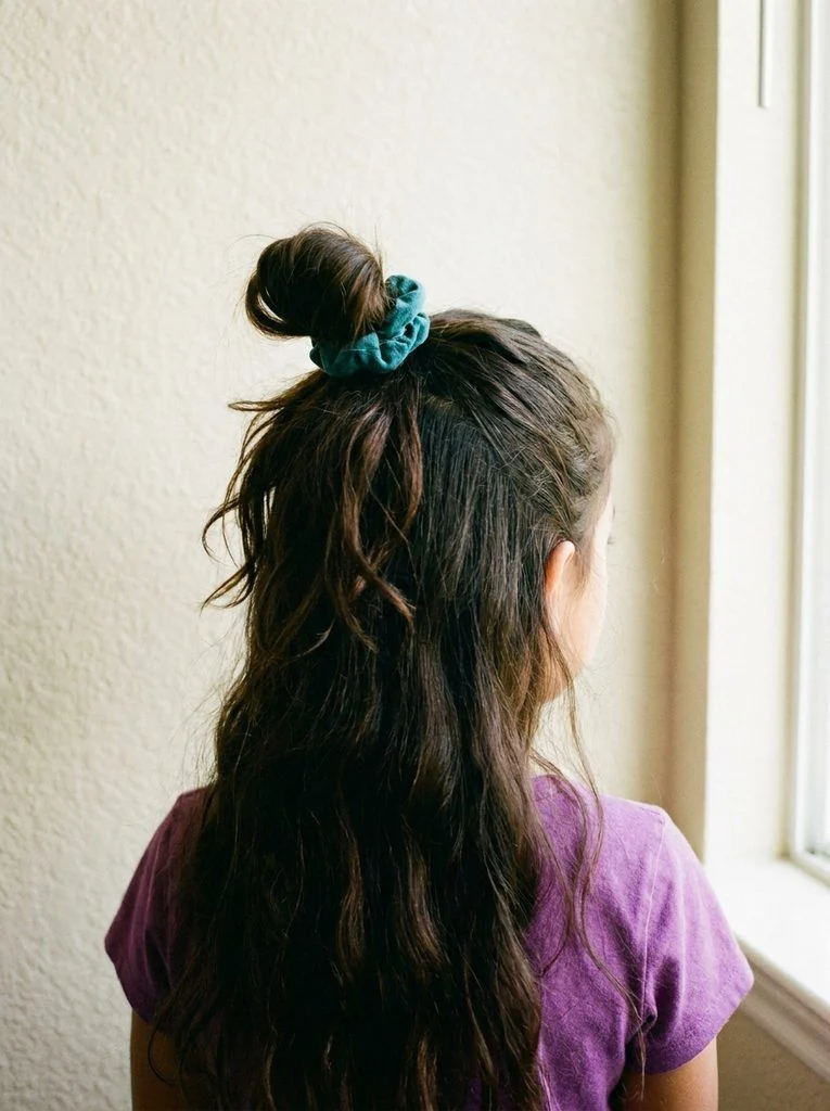 Relaxed high loop bun secured with a teal scrunchie.