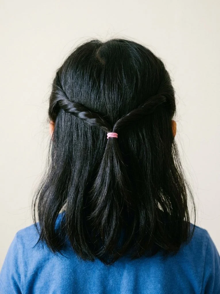 Two side twists joined with a pink tie above loose hair.