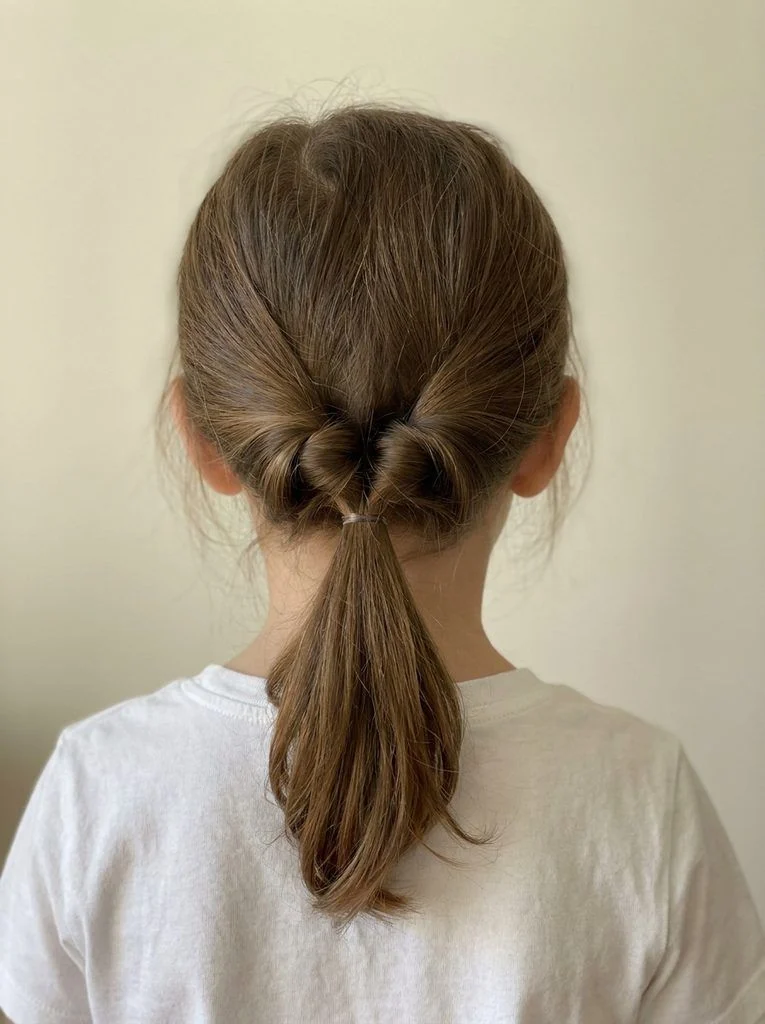 Low topsy-tail ponytail with inward twists above the hair tie.