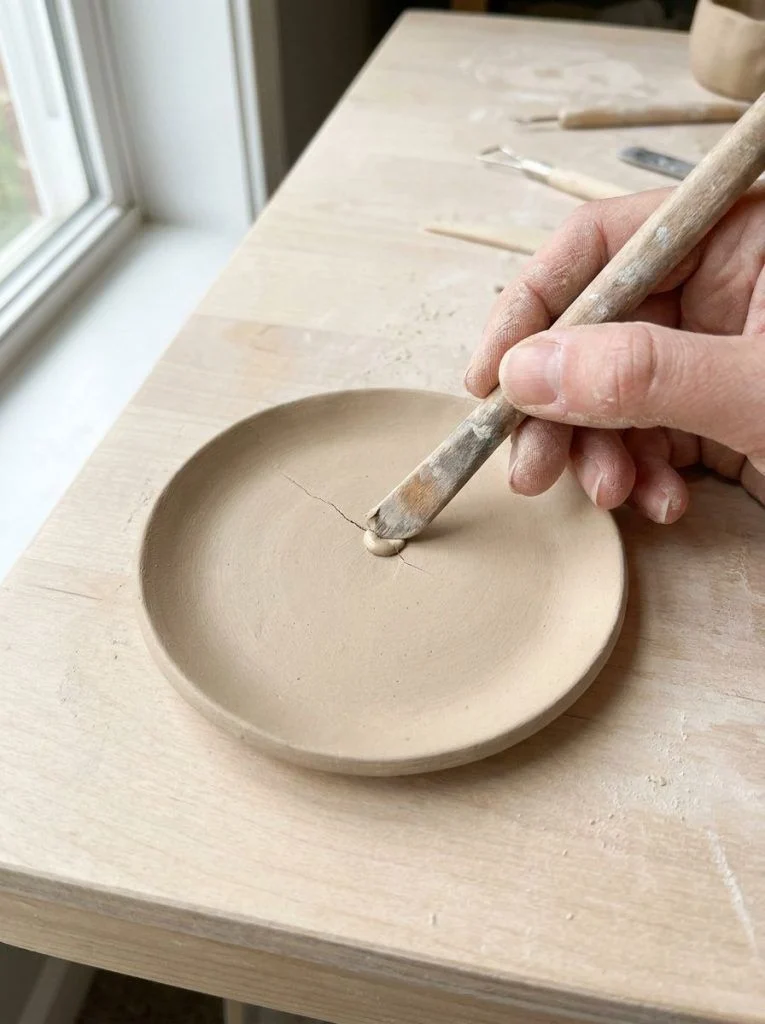 A small air-dry clay crack being filled with matching fresh clay