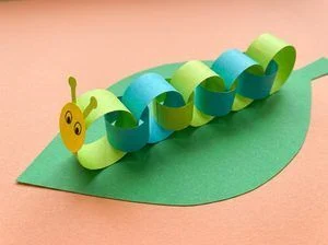 Green paper snake with an accordion body, drawn spots, and a red paper tongue.