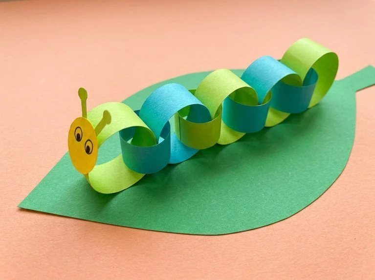 Green paper snake with an accordion body, drawn spots, and a red paper tongue.